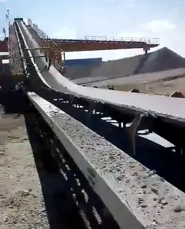 Trazado largo del transportador sobre el parque de minerales, con la banda sobre los rodillos y el pórtico de acero