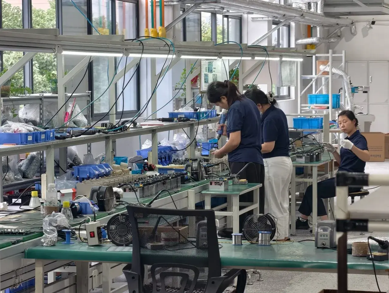 Operarios montando variadores en bancos de trabajo a lo largo de la línea de montaje