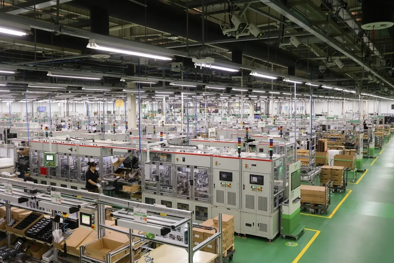 Vista elevada de la nave de montaje de Yolico: largas filas de armarios de variadores bajo el techo de la fábrica, ingenieros trabajando en los pasillos
